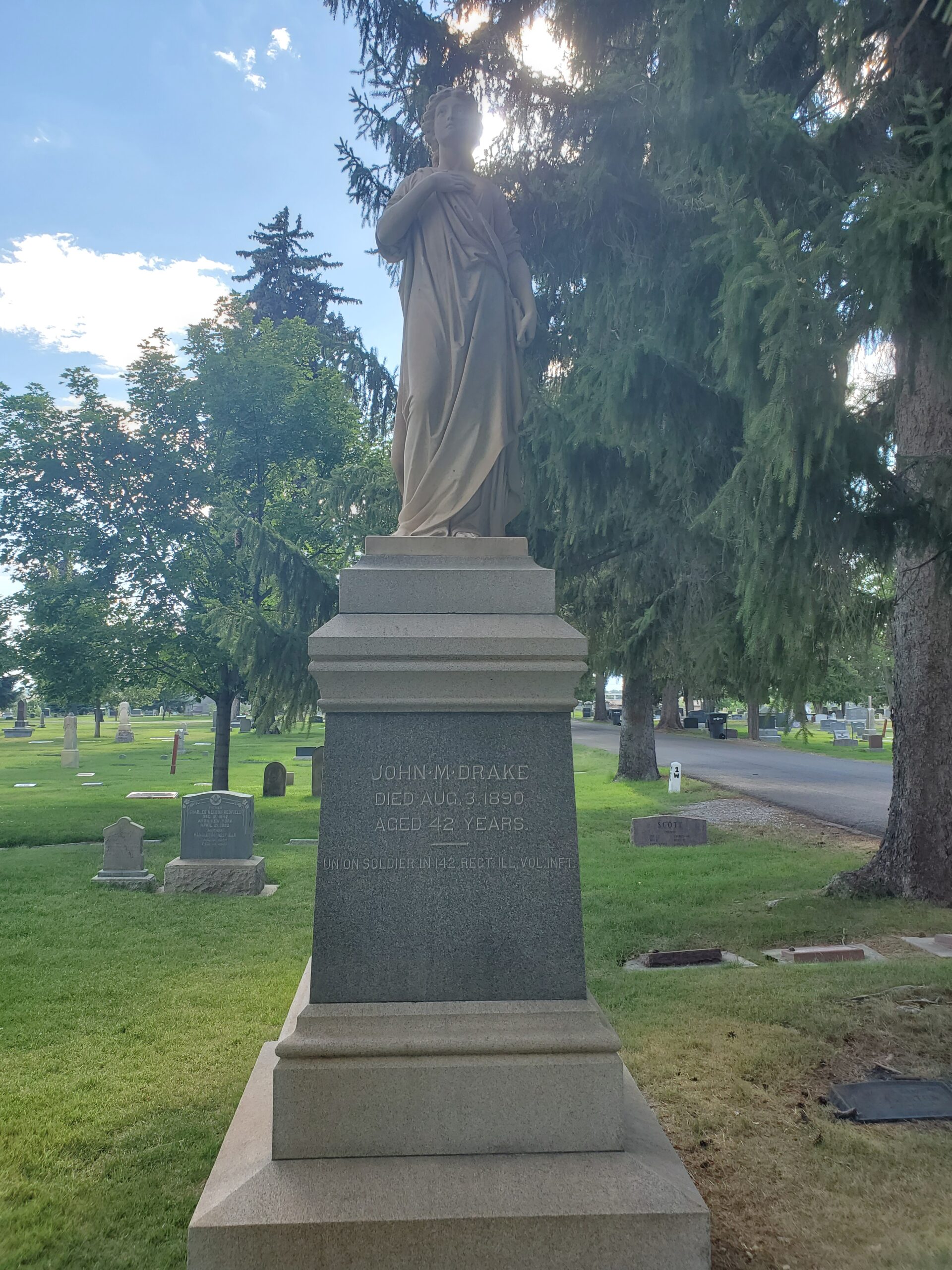 This grave is adorned with a white statue to top it